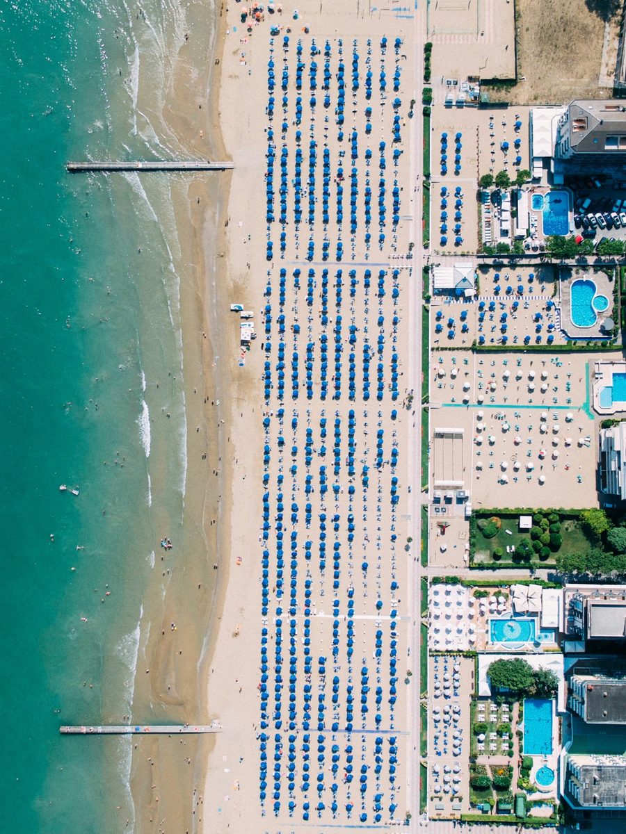 Jesolo beach from above: the sea, the sand and rows of blue umbrellas